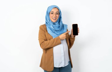 Gülümseyen, tesettürlü, Müslüman kadın tesettüre bürünmüş fotokopi odası gibi. Boş ekran ile işaret parmağı cep telefonu üzerinde