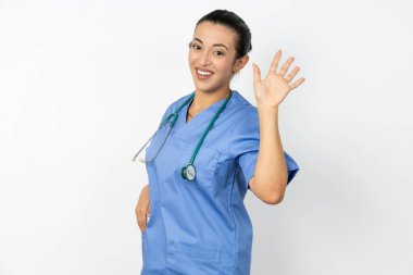 Mavi üniformalı Arap doktor merhaba diyerek mutlu ve güler yüzlü hoş geldin jesti yapıyor..