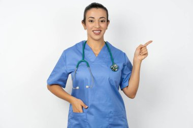 Arap doktor kadın mavi üniforma giyiyor. Kameraya bakıyor. Parmakların boş uzay satışlarını gösteriyor.
