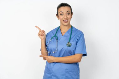 Üniformalı Arap kadın doktor fotokopi alanındaki steteskop noktalarıyla reklam için doğru yönü gösteriyor.