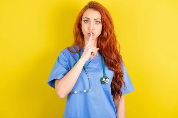 Surprised Young Red Haired Doctor Woman Makes Silence Gesture Keeps — Stock Photo, Image