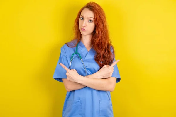 真剣な若い赤毛の医師の女性は 2つの項目間で躊躇する異なる側面で手とポイントを交差します ハード決定コンセプト — ストック写真