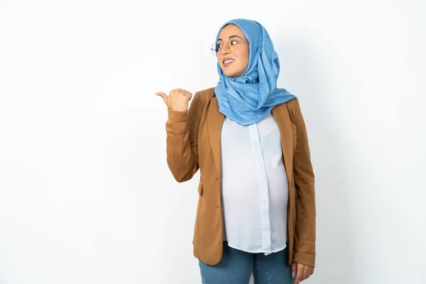 魅力的なイスラム教徒の妊婦は 広告を持っているコピースペースを見てヒジャーブを着ています — ストック写真