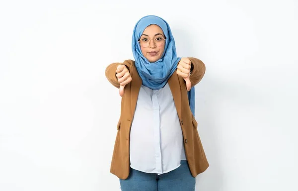 ヒジャーブを着ているイスラム教徒の妊婦は 両手で親指を見せて動揺しています 嫌いなコンセプト — ストック写真