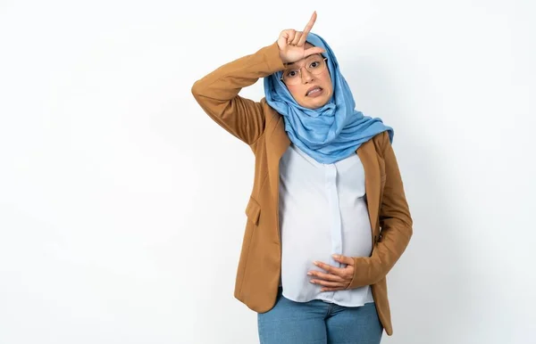 イスラム教徒の妊婦はヒジャーブを着て 額に指を持った人々をからかい 敗者のジェスチャーを嘲笑し侮辱する — ストック写真