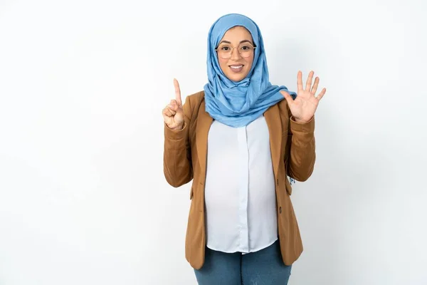 イスラム教徒の妊婦がヒジャーブを着て 自信と幸せを笑いながら指のナンバー6を指で指で指さす — ストック写真