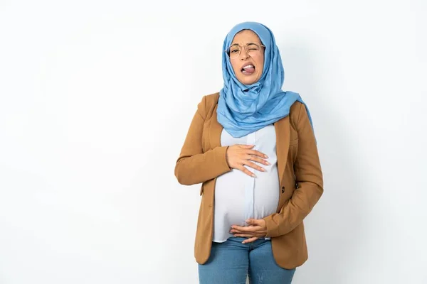 stock image muslim pregnant woman wearing hijab sticking tongue out happy with funny expression. Emotion concept.