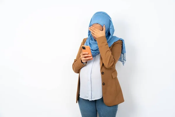 妊娠したイスラム教徒の女性は スマートフォンを見てヒジャーブを着て悲しい手を握っている感じ — ストック写真