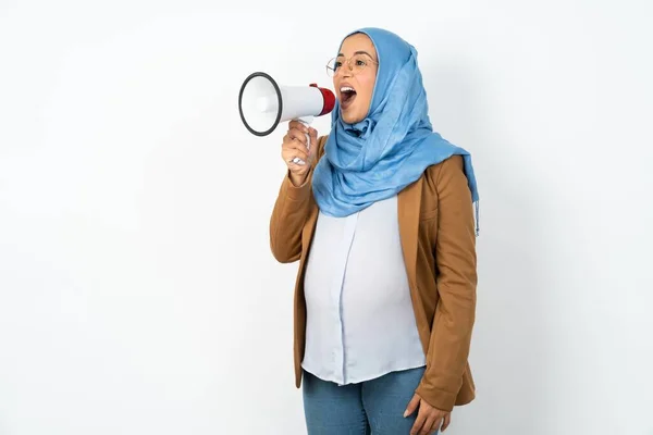 利用可能なコピースペースでメガフォンを通してヒジャブを着用している妊娠中のイスラム教徒の女性 — ストック写真