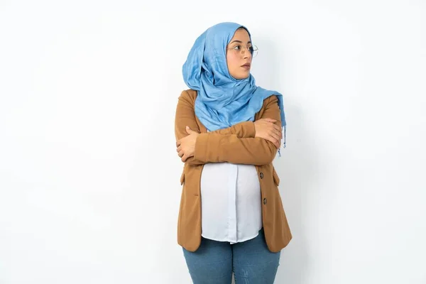 ヒジャーブを身に着けている思慮深い妊娠中のイスラム教徒の女性を魅了することは ペンギン式のどこかに集中した腕で立っています — ストック写真