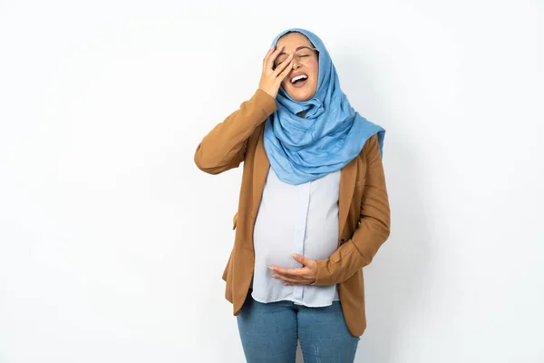 ヒジャーブを着ている美しい妊娠中のイスラム教徒の女性は 顔のヤシと笑顔を広くし 積極的に笑って面白いジョークのポーズを聞きます — ストック写真