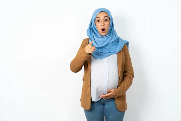 Schockierte Schöne Schwangere Muslimin Mit Hijab Zeigt Mit Fassungslosem Gesichtsausdruck — Stockfoto