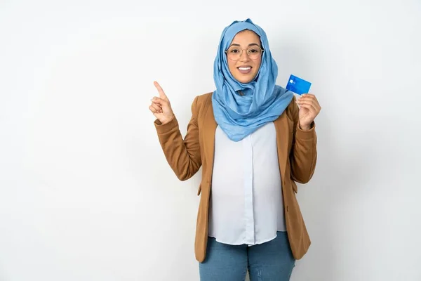 微笑美丽的怀孕的穆斯林女人 头戴头巾 露出借记卡 手指空空如也 — 图库照片