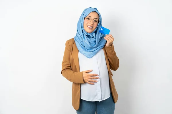 楽観的な美しい妊娠中のイスラム教徒の女性がヒジャブのホールドカードを着用した写真を閉じます — ストック写真