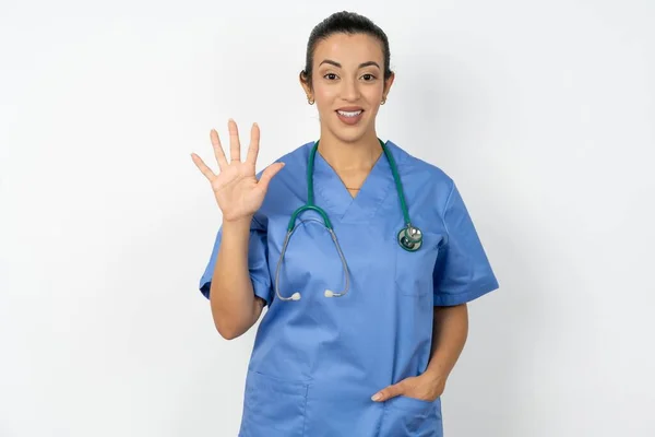 アラブの医師の女性は青い制服を着て自信と幸せを笑いながら指番号5を指で指で指を指さす — ストック写真