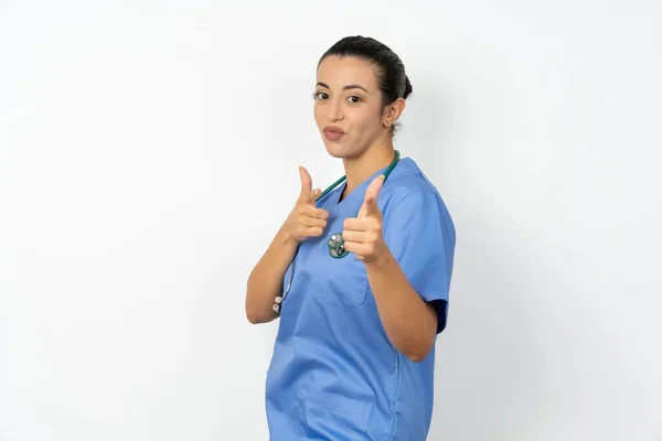青いユニフォームウィンクを着て カメラで指を指し 誰かを選択し 指ガンピストルを作る楽しいアラブの医師の女性 — ストック写真