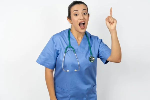 アラブの医師の女性は 青い制服を着て指を指し 天才的な思考に触発され 良いアイデアのサインを示し 頭の中で賢い解決策を持っています — ストック写真