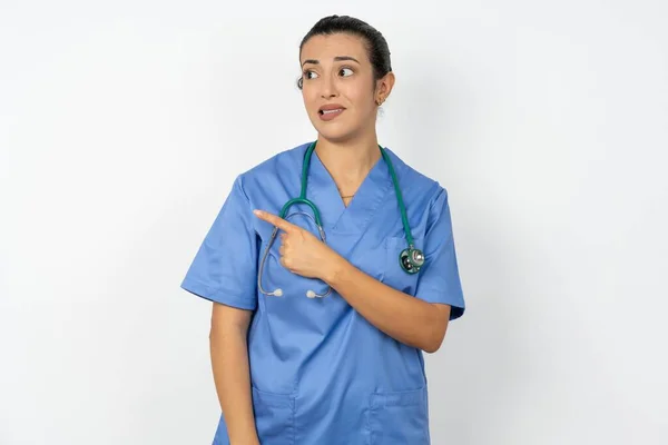 Árabe Médico Mulher Vestindo Azul Uniforme Apontando Para Lado Preocupado — Fotografia de Stock