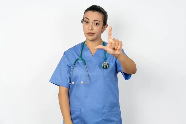 アラブの医師の女性 青い制服を着て額に指を持つ人々の楽しみを作る 敗者のジェスチャーを嘲笑し侮辱 — ストック写真