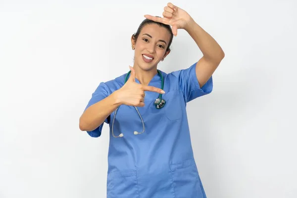 アラブの医師の女性は手で指のフレームを作る青い制服を着ています 創造性と写真コンセプト — ストック写真