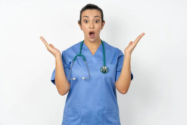 令人惊讶的医生女士身穿蓝色制服 神智不清 凝视着镜头 困惑不已 不知道如何回答棘手的问题 肢体语言 情感观念 — 图库照片