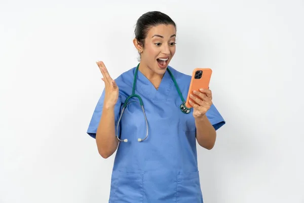 アラブの医師の女性は 手の細胞の読書ニュースを保持する青い制服を着ています — ストック写真