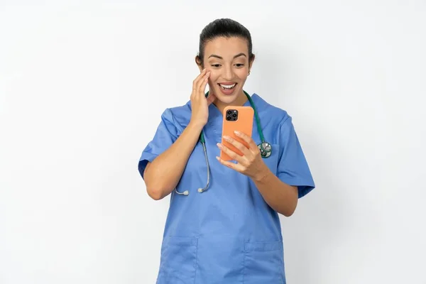 使用新应用5G的Arab医生女士 身穿蓝色制服 手持手机阅读短信 — 图库照片