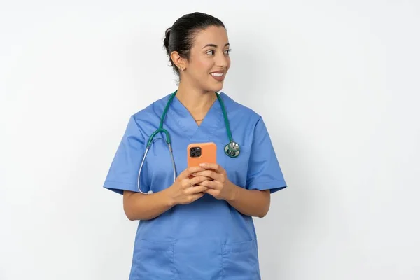 Arabski Lekarz Kobieta Noszenie Niebieski Mundur Trzymać Telefon Ręce Czytać — Zdjęcie stockowe