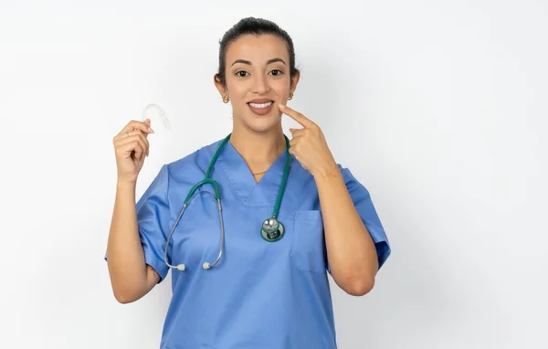 アラブの女性医師は 目に見えない異星人を保持し 完璧なまっすぐな歯を指しているステススコープと制服を着ています 歯科医療と自信のコンセプト — ストック写真