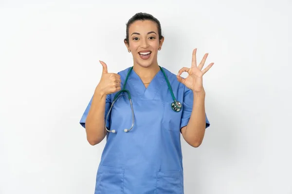 アラブの女性医師 笑顔と見て制服を着て ケアフリーでポジティブ 片手で勝利や平和 — ストック写真