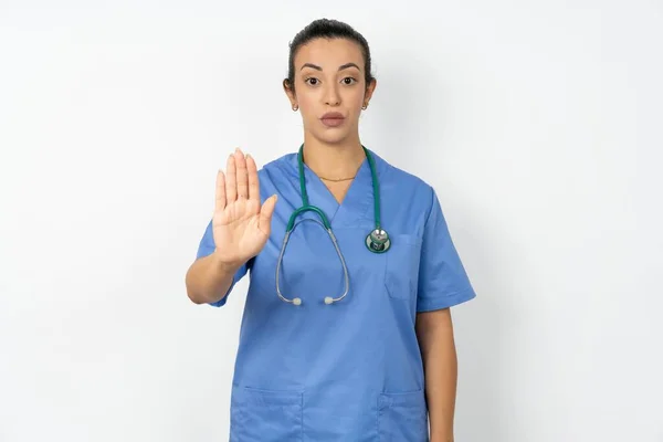 アラブの女性医師は ステスコープと制服を着たショーストップサイン禁止シンボルは 厳密な表現でカメラにパームを前進させます — ストック写真