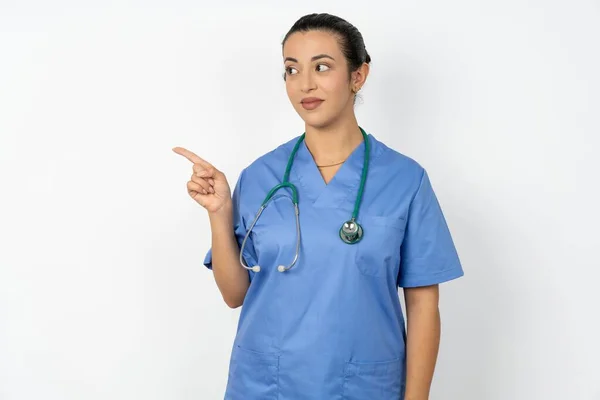 アラブ女性医師 コピースペースでステスコープポイントと制服を着て 何かを宣伝 アドバイス最高の価格 — ストック写真
