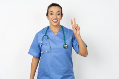Mavi üniforma giyen pozitif Arap doktor. Selfie çekin. V işareti yapın.