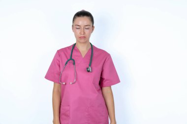 Pembe üniformalı beyaz kadın doktor. Gözlerinde yaşlar, acı ve depresyon yüzünden çaresizce ağlıyor. Üzgün yüz ifadesi ve duygu konsepti.