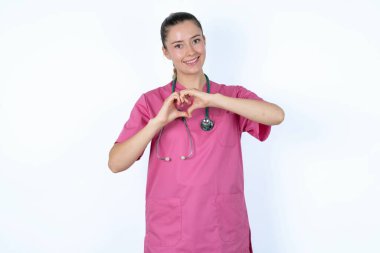 Pembe üniformalı beyaz kadın doktor. Steteskopla gülümsüyor. Aşkla gülümsüyor. Romantik konsept.