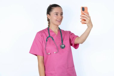 Kafkas kadın doktor, izole edilmiş bir fotoğraf, cep telefonuyla selfie çekiyor. İnsanlar, teknoloji ve eğlence kavramı