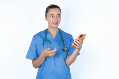 Mutlu kadın doktor avuç içi kaldırır ve cep telefonu kullanır. Kısa mesaj ya da video görüşmeleri için yüksek hızlı internet kullanır.