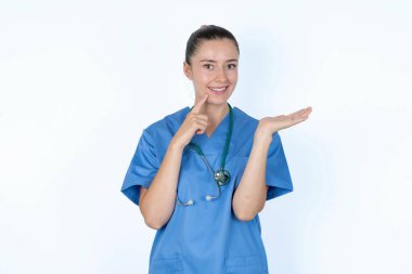 Steteskop reklamıyla beyaz kadın doktor parmak ile dişlere dokunuyor..