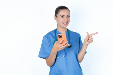 Steteskoplu beyaz kadın doktor telefonunu tutuyor ve boş fotokopi alanını işaret ediyor.