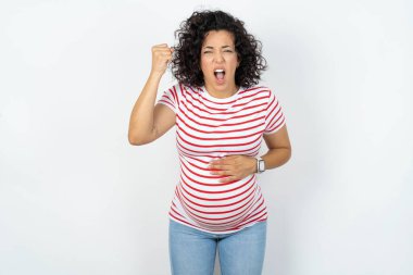 pregnant woman angry and mad raising fist frustrated and furious while shouting with anger. Rage and aggressive concept. clipart