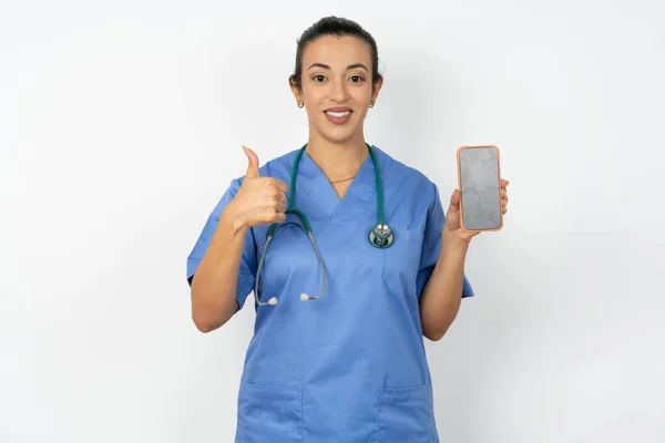穿着蓝色制服的医生女士显示空白屏幕智能手机 大拇指向上推荐新应用程序 — 图库照片