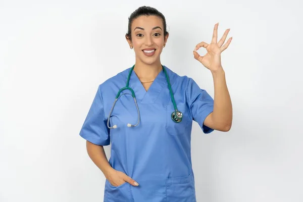 青い制服を着ているアラブの医師の女性は 手の腕のオキーのシンボルは 新鮮なニュースをアドバイスすることを承認します — ストック写真