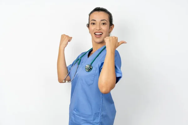 stock image Hooray arab doctor woman wearing blue uniform  point back empty space 