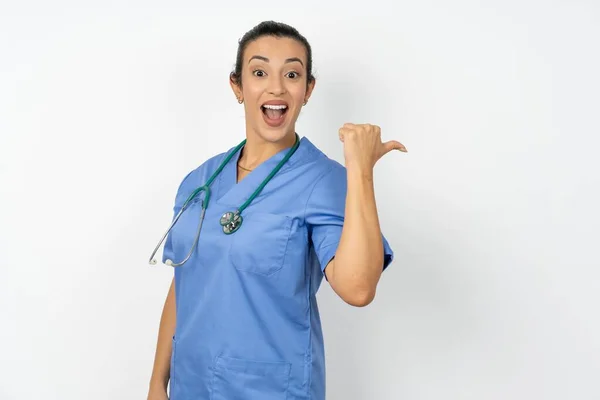 ブルーユニフォームのポイントバック空のスペースを身に着けている印象的なアラブの医師の女性 — ストック写真