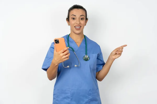 Sorpresa Araba Donna Medico Indossando Uniforme Blu Tenendo Telefono Puntando — Foto Stock
