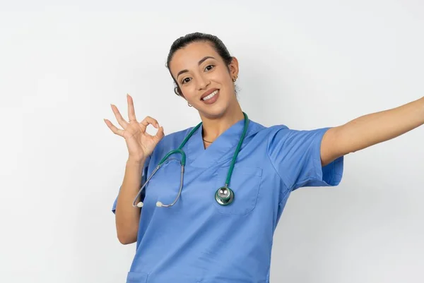青い制服を着ている美しいアラブの医師の女性の肖像画は セルフィーショーオキーシンボルを作ります — ストック写真