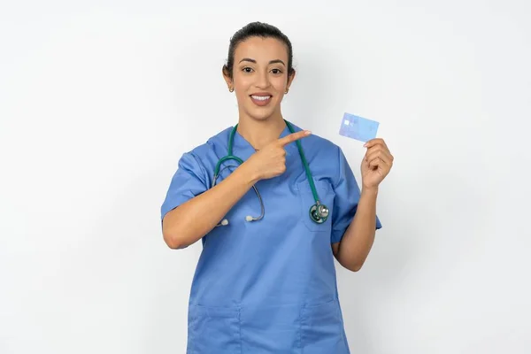 穿着蓝色制服的阿拉伯医生用手指银行卡购物的照片 — 图库照片