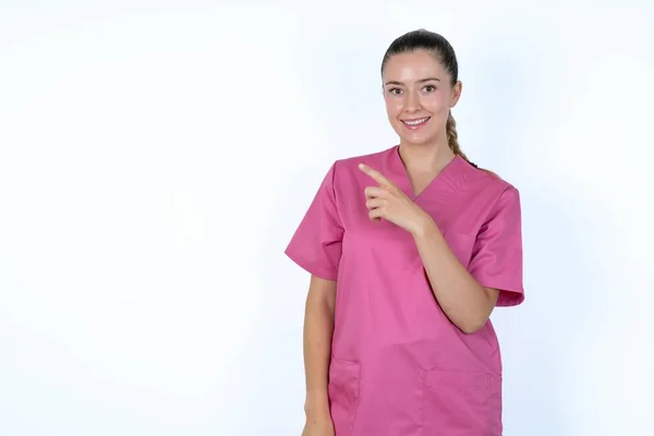 白人女性の医者は ピンクの制服を着て あなたに微笑みかけます そこを見渡して — ストック写真