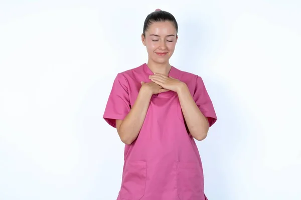 Biała Kobieta Lekarz Różowym Mundurze Zamyka Oczy Trzyma Ręce Klatce — Zdjęcie stockowe