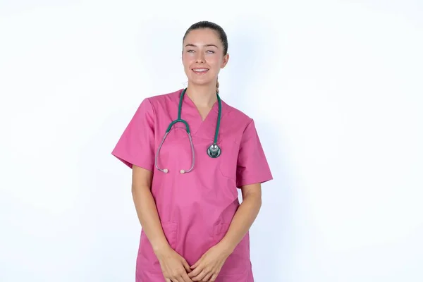 謎の笑顔を見上げたステスコープでピンクのユニフォームのミステリアスなカウカシアの女性医師の肖像画 広告コンセプト — ストック写真